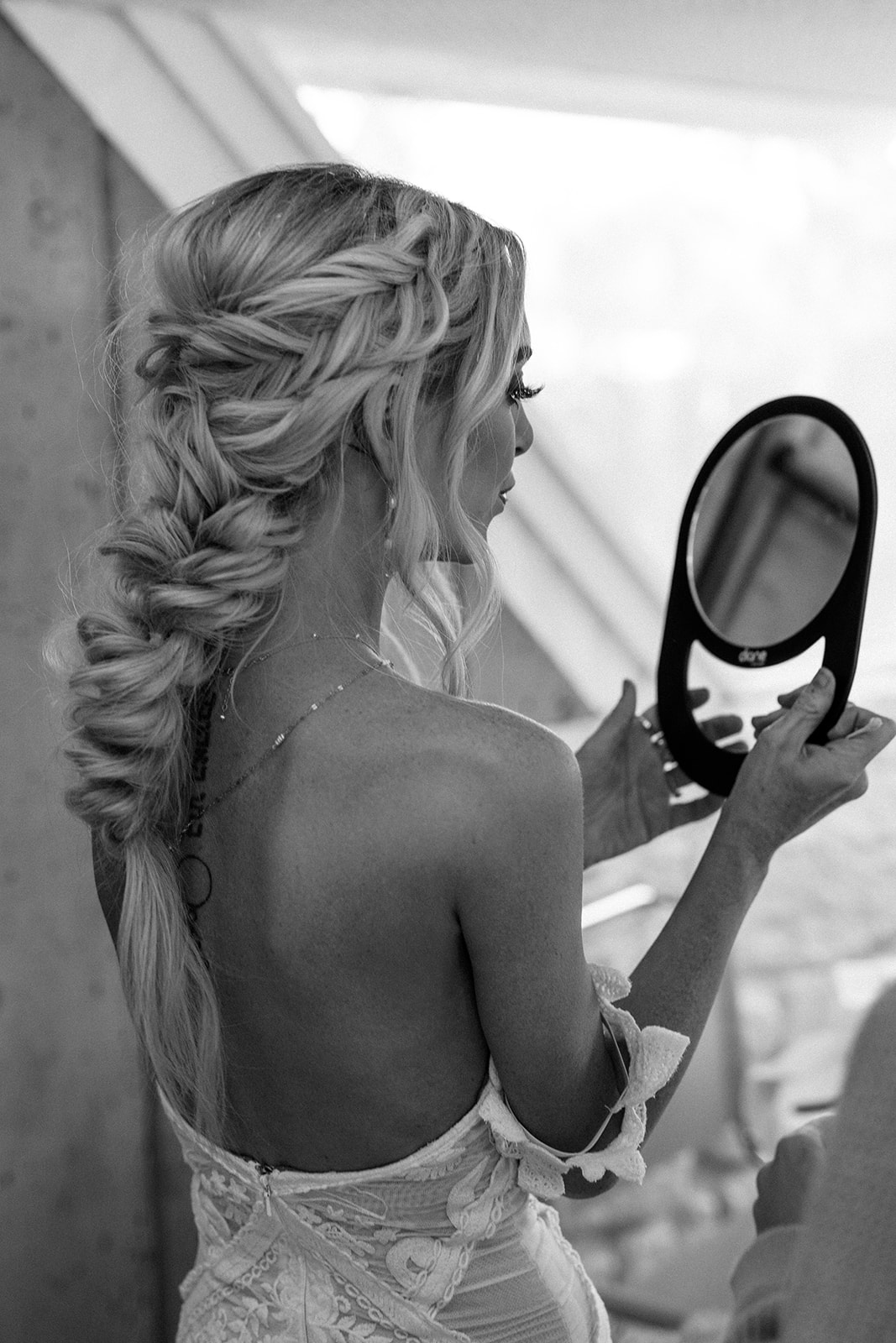 woman looking into mirror with braid in hair for wedding hair