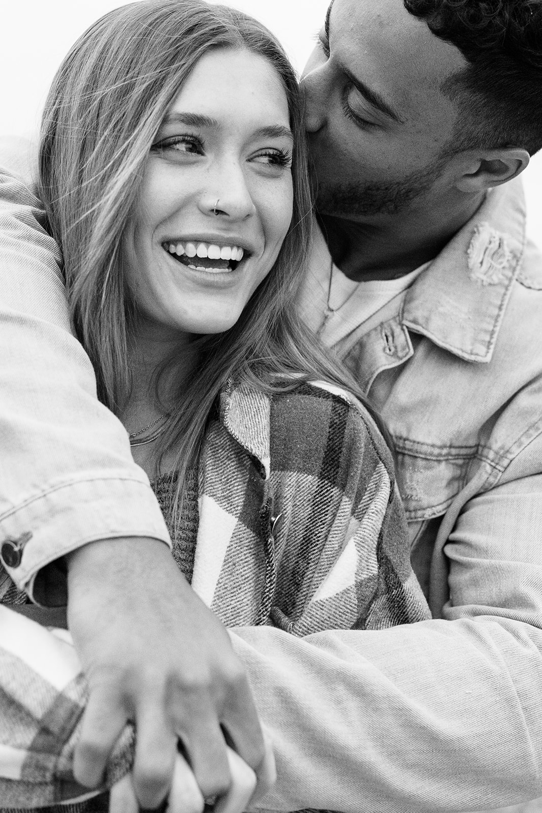 woman smiling while man kisses her head during a couples photoshoot 