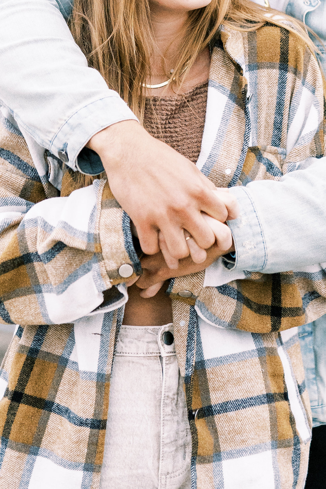 woman and man holding hands during couples photoshoot. Woman wearing brown flannel and man wearing jean jacket. Texas couples photographer