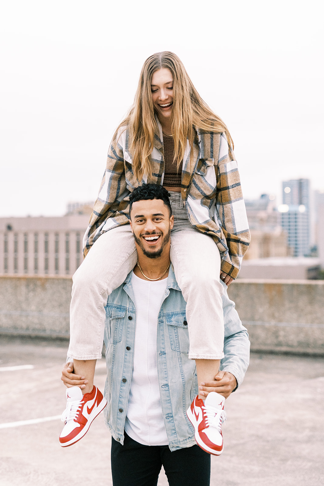 woman sitting on mans shoulders while both are laughing
