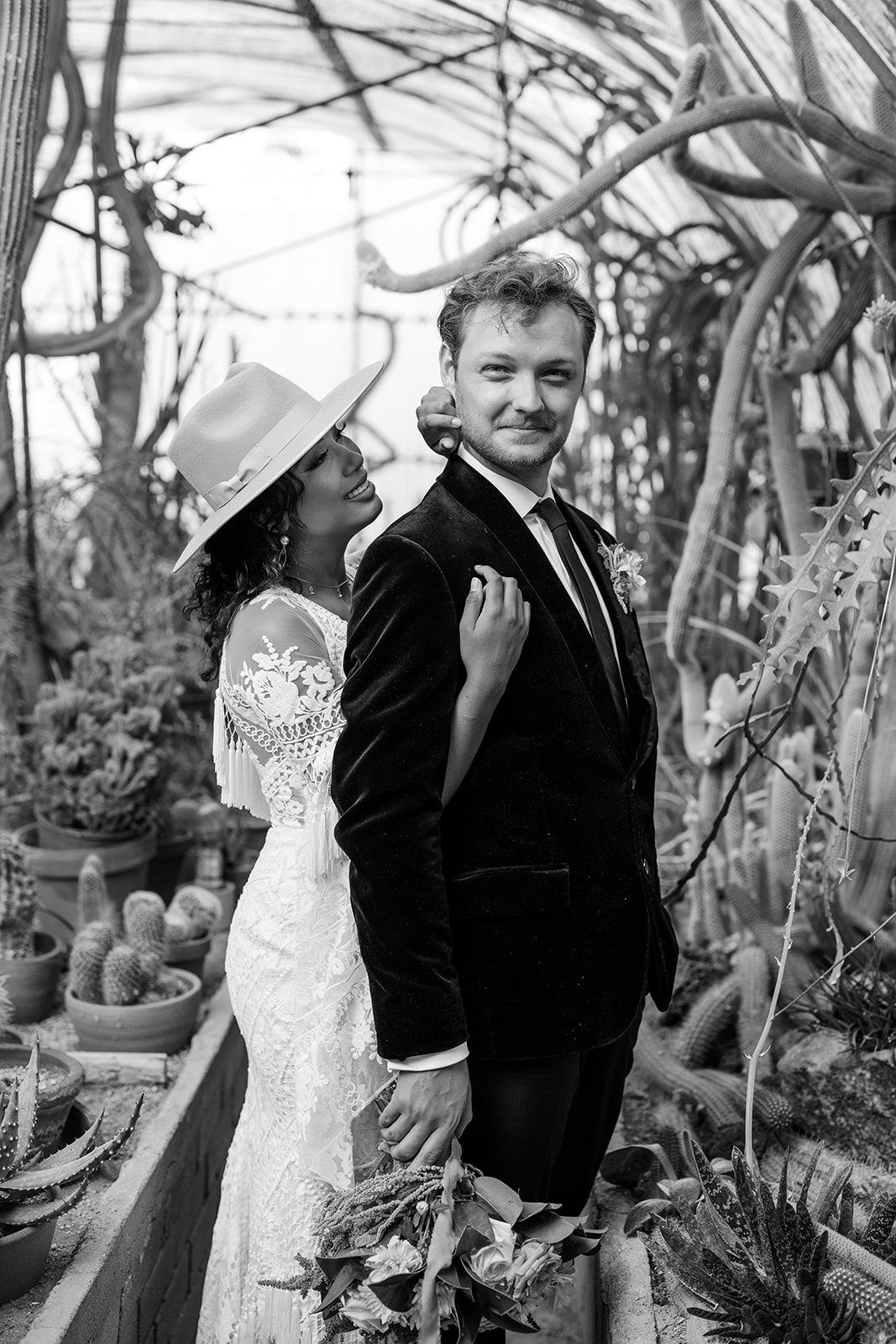 Black and white image of woman and man surrounded by desert plants. 