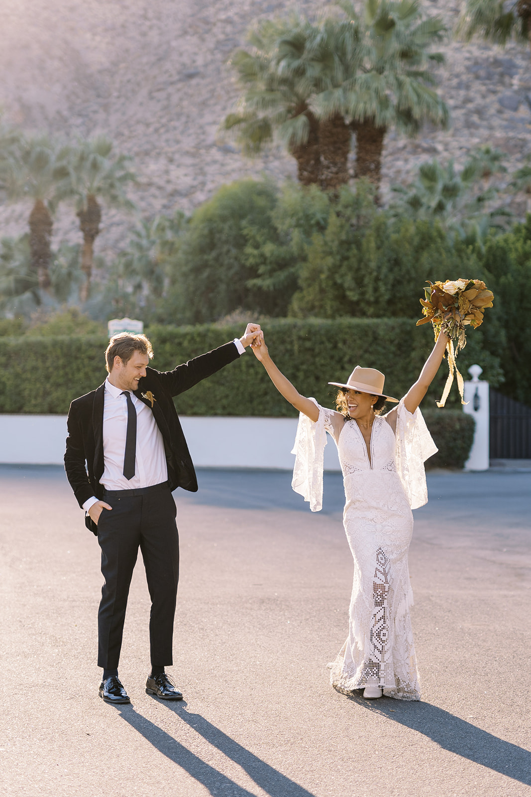 Man and woman holding hands while arms are up in the air after their desert elopement. 