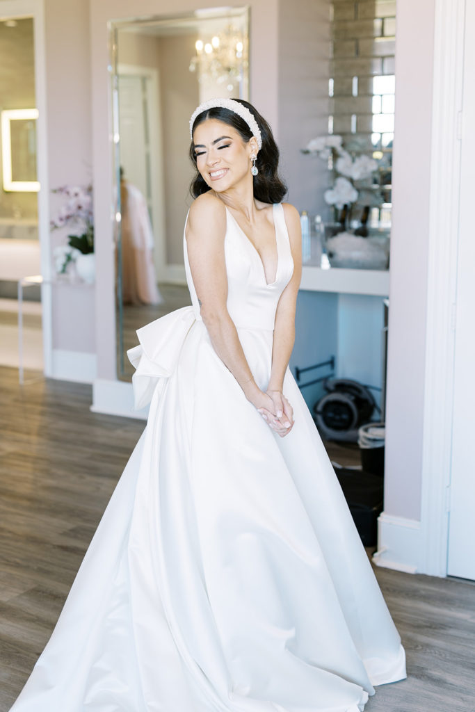 Bride smiling with her eyes closed while wearing wedding dress and showing bridesmaids. Texas Wedding Photography