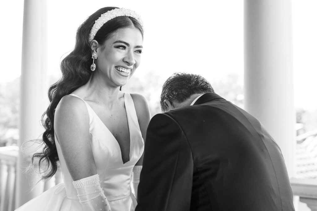 Bride laughing with father with tears in her eyes during their first look for wedding photos. 