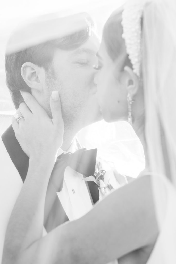 Bride and Groom kissing underneath wedding veil. Black and white wedding photos