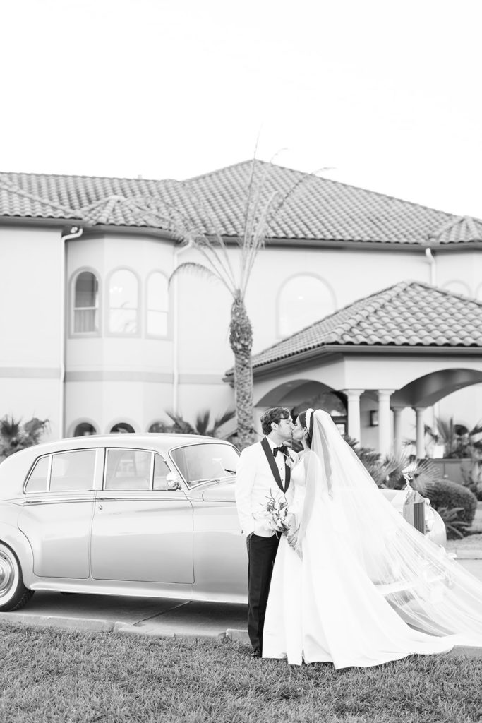 Bride and groom kissing near vintage car. Vintage rolls royce for wedding photos. Black and white wedding photos.