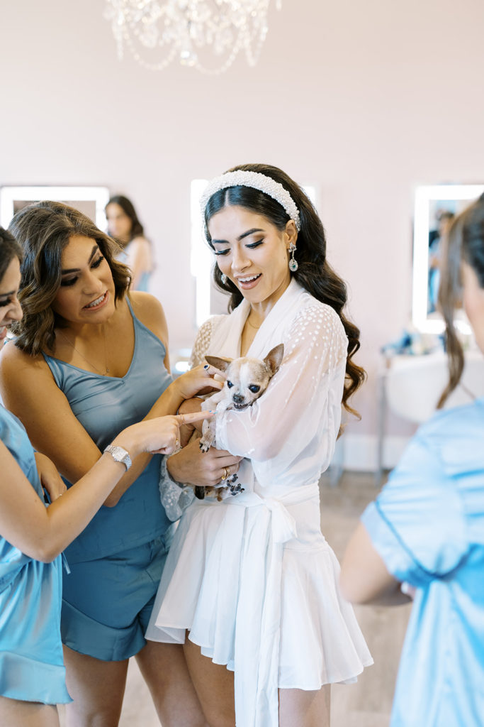 Bride holding her dog while getting ready for wedding day. Blue bridesmaid pajamas. Texas wedding photography