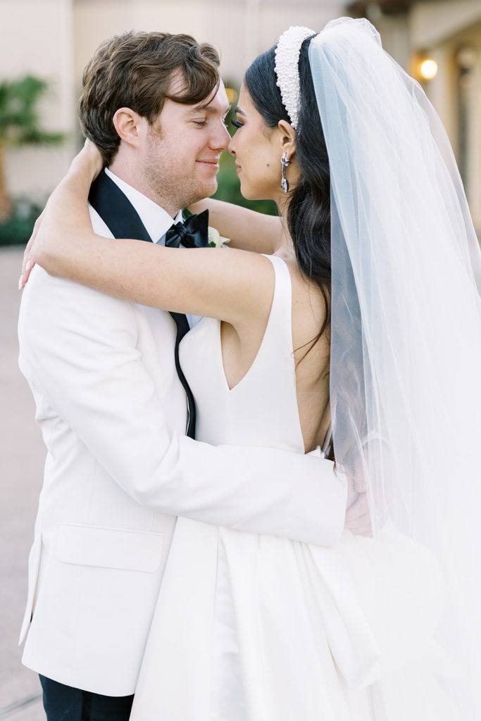 Bride and groom touching noses and hugging each other in wedding attire. Texas wedding photography.