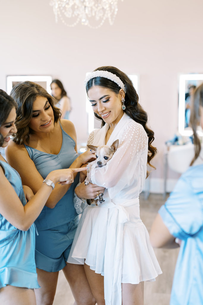 Bride holding her dog while getting ready for wedding day. Blue bridesmaid pajamas. Texas wedding photography