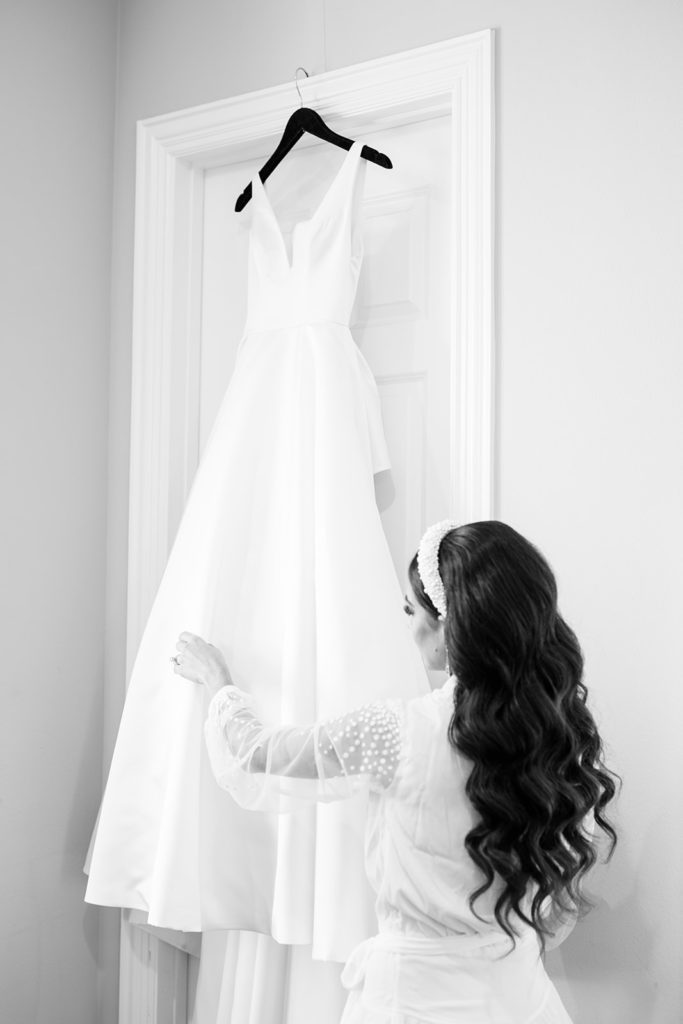 Bride looking at wedding dress after hair and makeup for wedding day. Black and white wedding photography in Texas.
