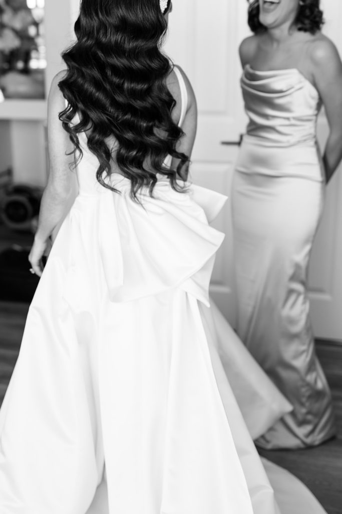 Bride wearing dress and laughing with bridesmaid. Getting ready wedding photos in black and white. Texas wedding photography