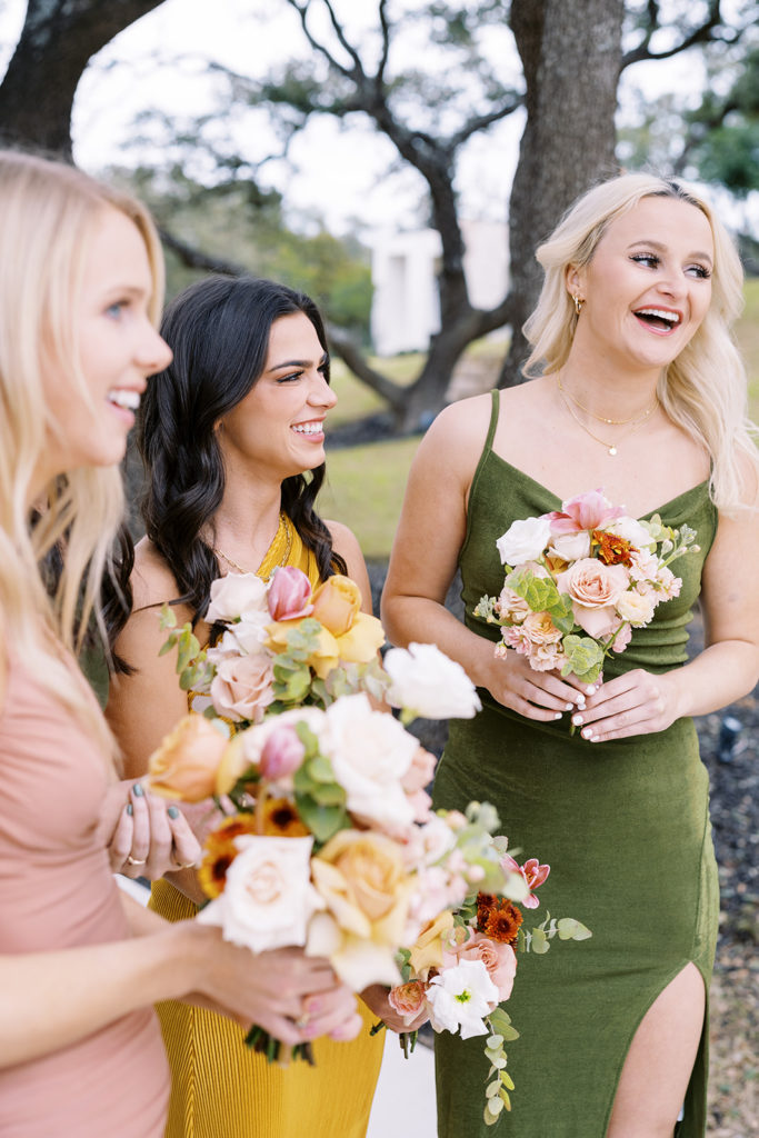 bridesmaids smiling and holding flower bouquets at wedding venue in Texas