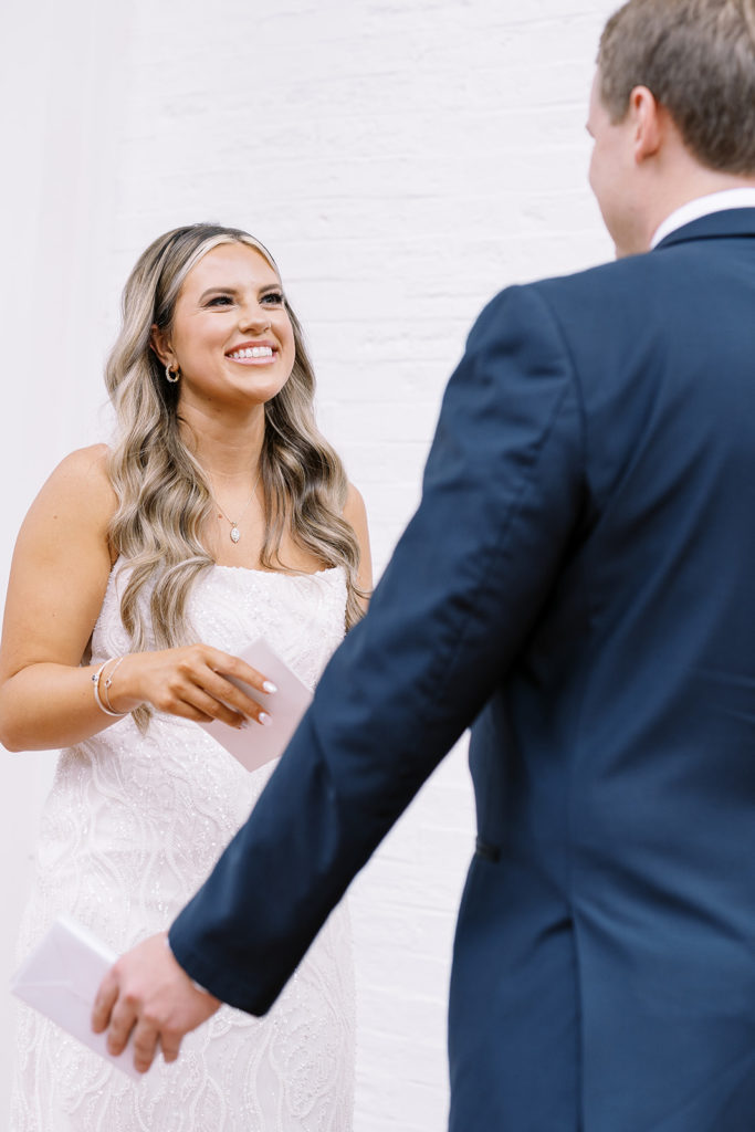 bride smiling at groom and holding a piece of paper