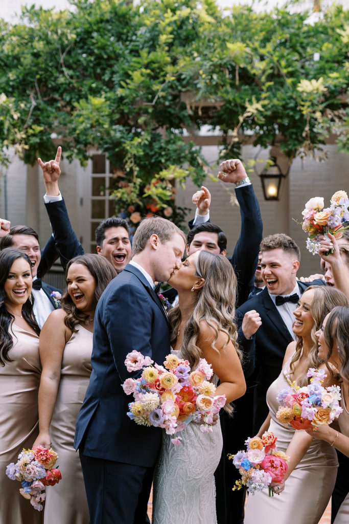 bridal party cheering for bride and groom while bride and groom are kissing