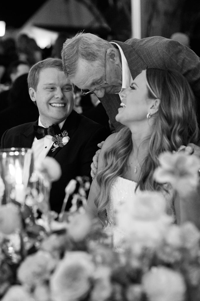 bride and groom smiling and laughing with each other while talking to guests - black and white wedding photos