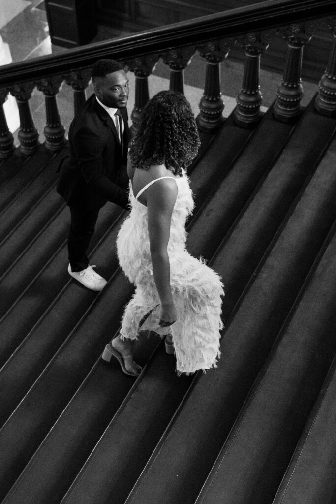 woman and man walking up stairs while holding hands