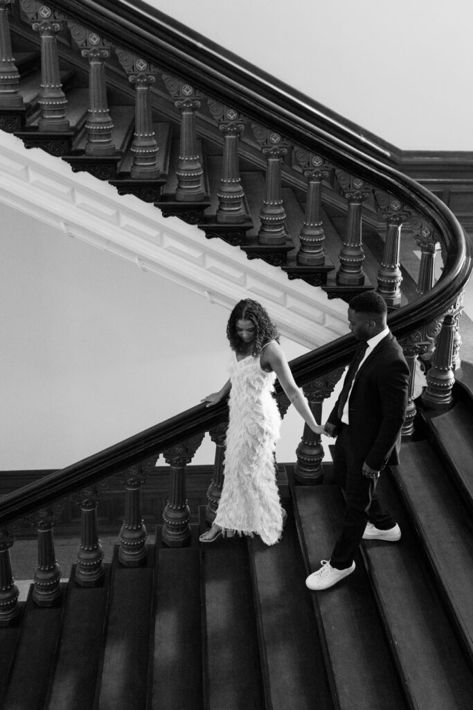 woman and man holding hands while walking down stairs for engagement photos