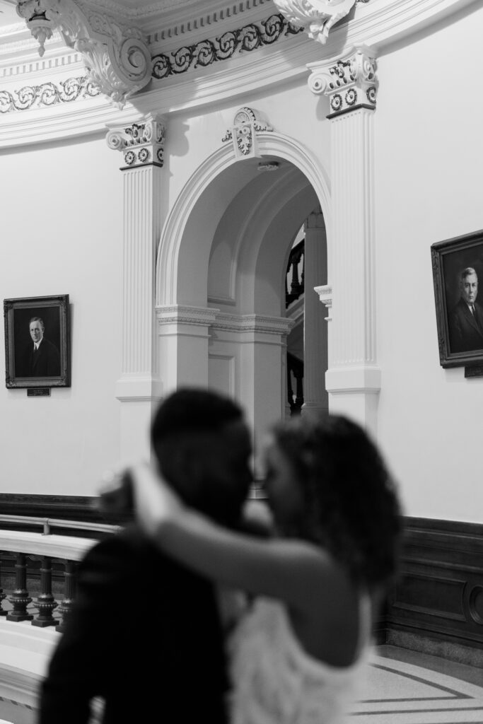 blurry image of man and woman inside of texas capitol holding each other for engagement photos